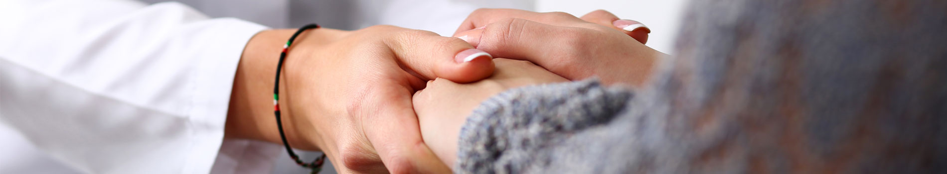A provider holds the hands of a patient